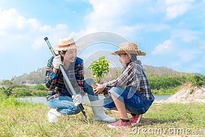 Asian Mom and child girl plant sapling tree in the nature spring for reduce global warming growth feature, Stock Photo